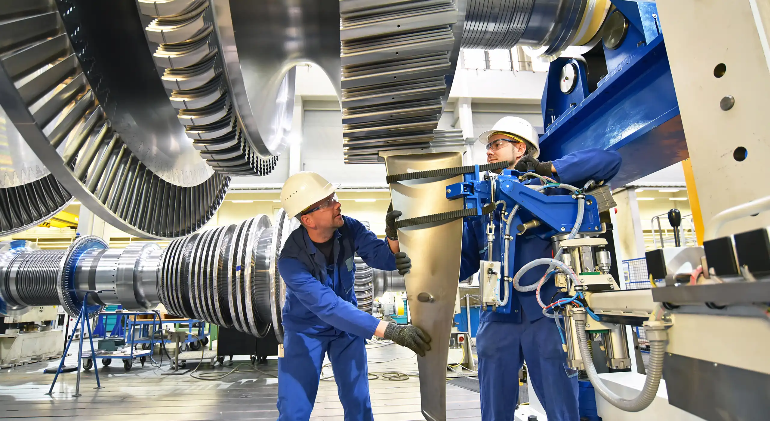 Zwei Ingenieure arbeiten gemeinsam an einer grossen Industrieturbine. Das Bild zeigt präzise Teamarbeit, technisches Know-how und Zusammenarbeit im Maschinenbau – zentrale Werte der InnoExperts Group für Innovation und wirksame Führung.